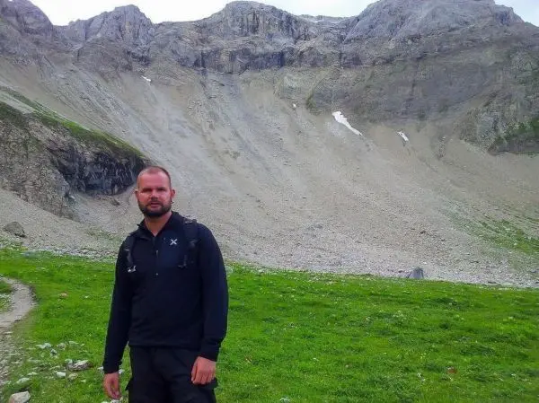 Mann steht auf einem Wanderweg vor einer steilen Berglandschaft