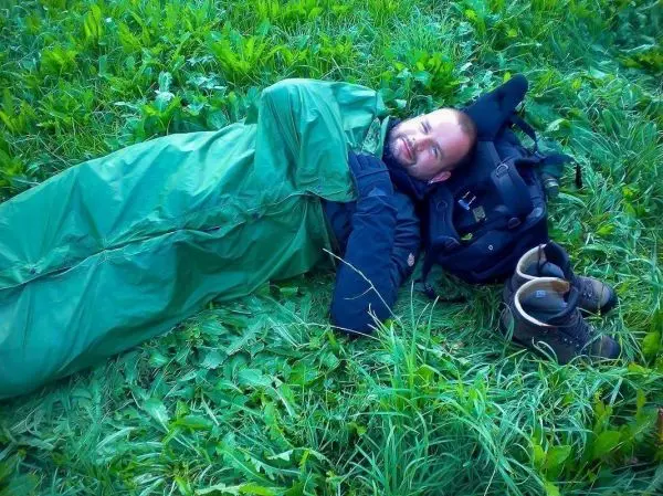 Schlafsack liegt auf Gras, Rucksack und Schuhe daneben