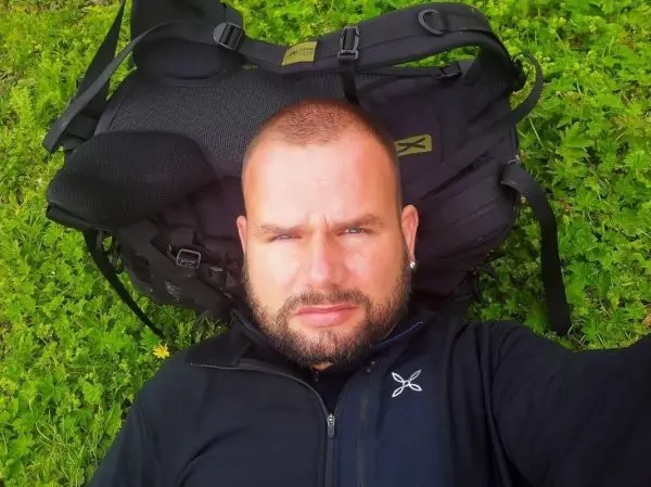 Schwarze Jacke liegt auf grünem Gras neben einem Rucksack