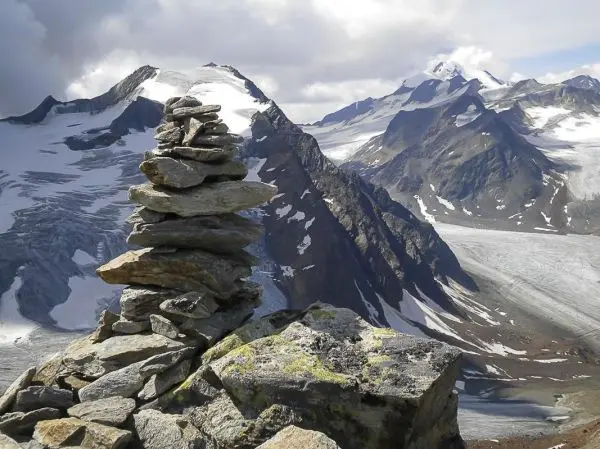 Steinhaufen auf einem Berggipfel mit schneebedeckten Gipfeln im Hintergrund