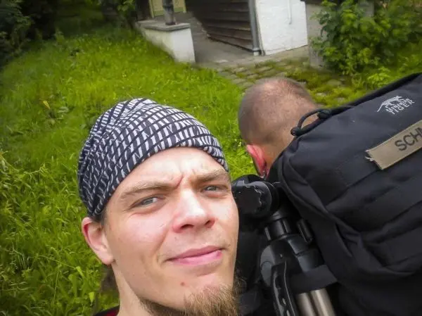 Zwei Personen mit Rucksäcken stehen in einer grünen Umgebung