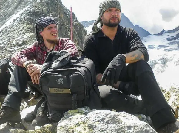 Zwei Personen sitzen auf einem Felsen mit Rucksack in bergiger Umgebung