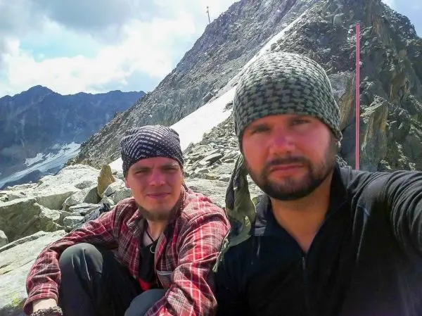 Zwei Personen sitzen auf einem felsigen Untergrund in bergiger Umgebung