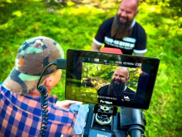 Kamera filmt zwei Männer im Gespräch auf einer Wiese