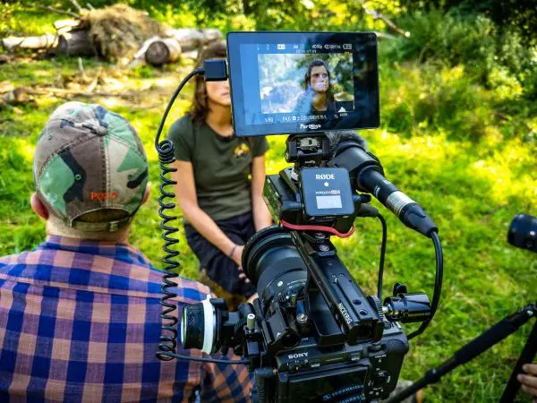 Kamera mit Mikrofon filmt Interview in der Natur, zwei Personen im Fokus