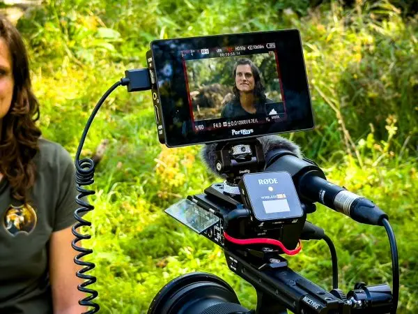 Kamera mit Monitor und Mikrofon auf einem Stativ, Aufnahme im Freien