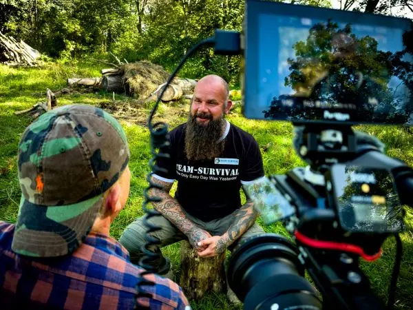 Zwei Personen sitzen im Freien, eine Kamera filmt das Gespräch