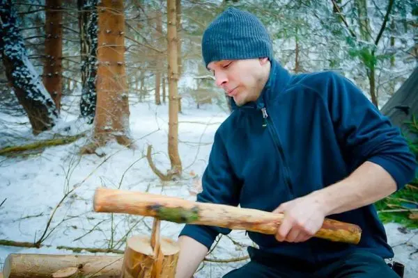 Person bearbeitet Holz im Schneewald