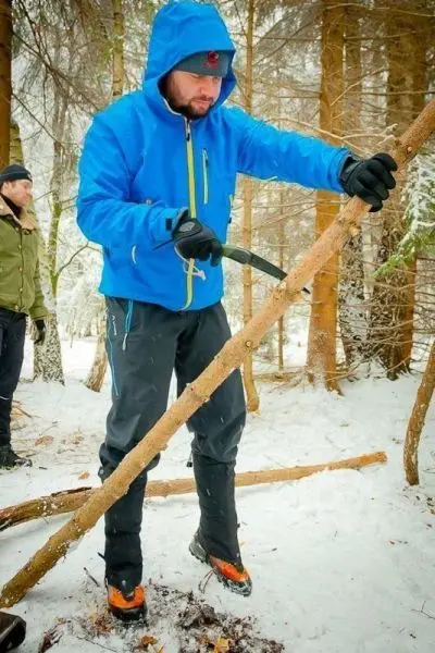 Person in blauer Jacke bearbeitet einen Stock im Schnee