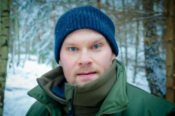 Person mit blauen Augen und Mütze im Schneewald