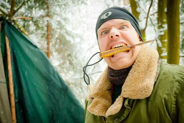 Person mit Holzstück im Mund in verschneiter Umgebung