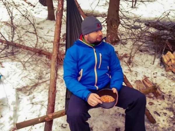 Person sitzt im Schnee und hält eine Schüssel mit Essen