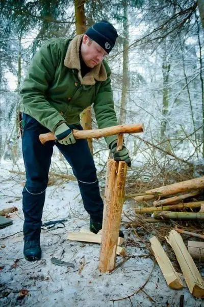 Person spaltet Holz im Wald mit einem Stock