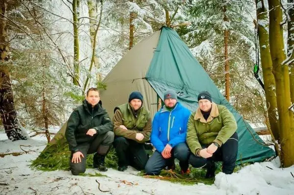 Vier Personen posieren vor einem Zelt im Schnee