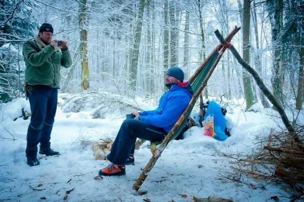 Zwei Personen im Schnee, eine sitzt, die andere fotografiert