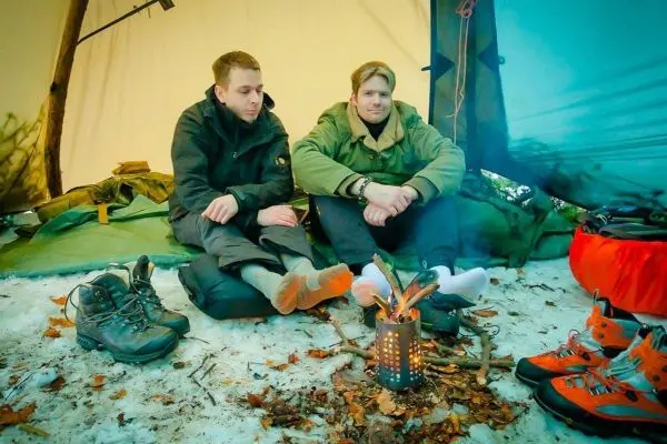 Zwei Personen sitzen im Zelt vor einem kleinen Feuer