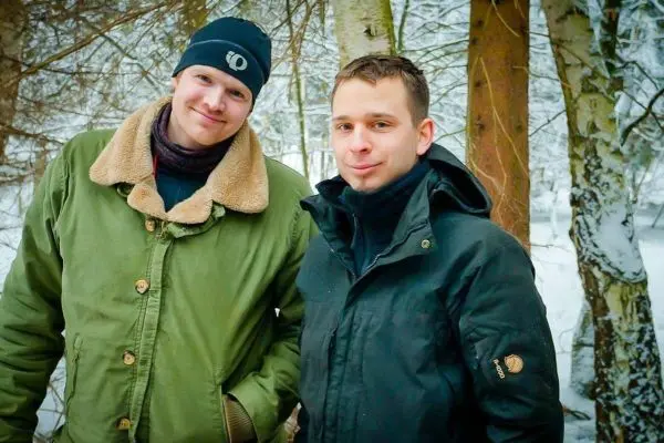 Zwei Personen stehen im Schnee zwischen Bäumen