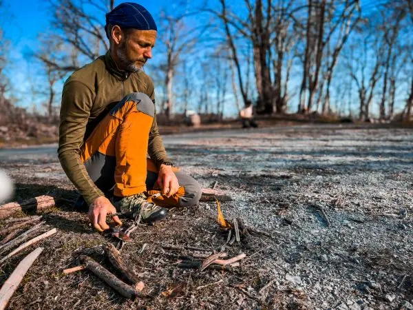 Feuerstahl erzeugt Funken auf Zunder zwischen Holzstücken