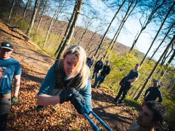 Frau zieht an einem Seil, während andere Teilnehmer beobachten