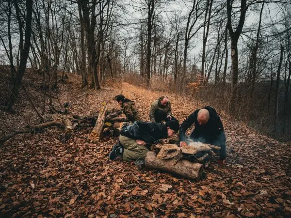 Gruppe arbeitet an einem kleinen Feuer aus Holz und Laub