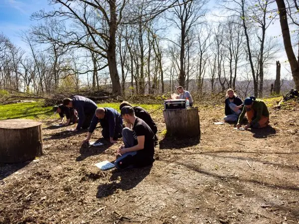 Gruppenteilnehmer sitzen auf dem Boden und schreiben auf Notizblättern