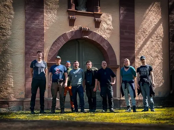 Gruppierung von acht Personen vor einer historischen Gebäudefassade