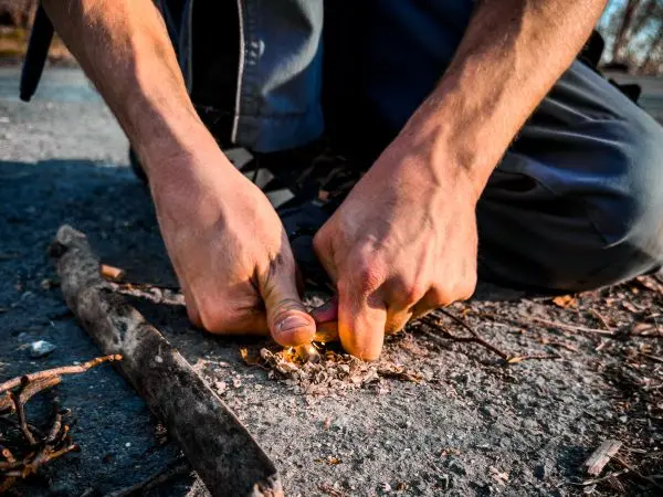 Hände zundernd auf einem Haufen Zunder, um Funken zu erzeugen