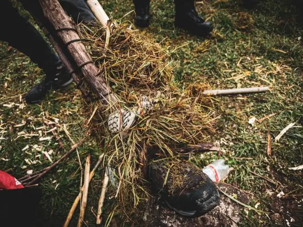 Improvisierte Trage mit Gras und Holzstücken um einen Stiefel gewickelt