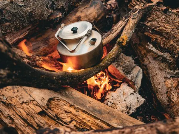 Kessel hängt über einem kleinen Feuer zwischen Holzstücken