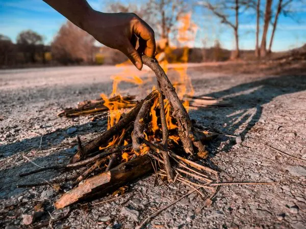 Kleine Flamme brennt zwischen Holzstücken auf dem Boden