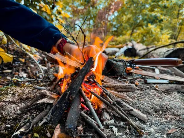 Kleine Flamme brennt zwischen Holzstücken auf dem Boden