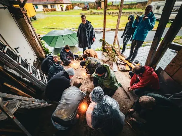 Kleine Flamme entsteht aus Zunder in einer Gruppe um ein Feuer