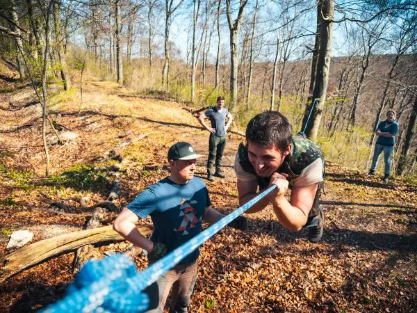 Mann überquert selbstgebaute Seilbrücke, während andere zuschauen