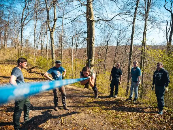 Mann überquert selbstgebaute Seilbrücke, während andere zuschauen