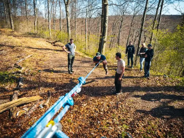 Mann überquert selbstgebaute Seilbrücke, während andere zuschauen