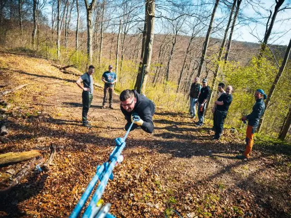 Mann zieht an einem Seil, während andere zuschauen und die Umgebung erkunden