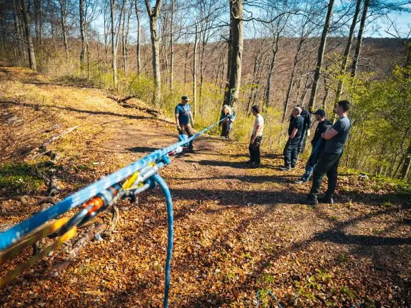 Seilquerung mit mehreren Personen an einem Hang im Wald