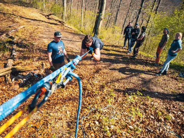 Seilquerung mit selbstgebauter Seilbrücke über Laubboden, Teilnehmer unterstützen