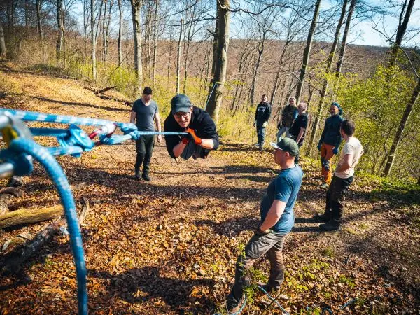 Selbstgebaute Seilquerung wird von einer Person überquert, während andere zuschauen