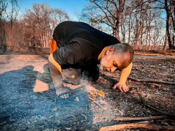 Zunder glimmt in der Nähe von kleinen Ästen und trockenem Laub