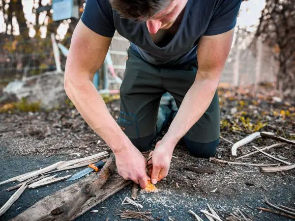 Zunder wird mit einem Messer auf einem Holzstück bearbeitet