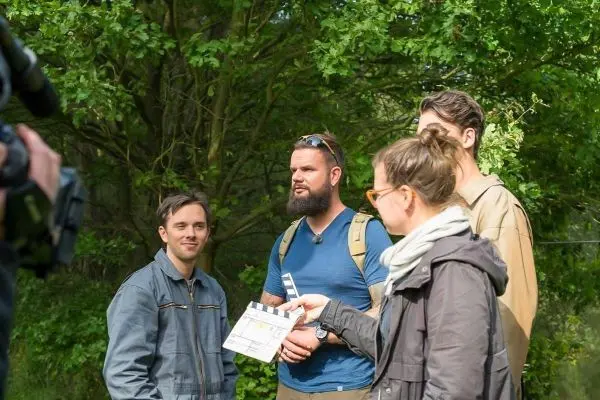 Gruppe diskutiert mit Klappe in der Hand im Wald