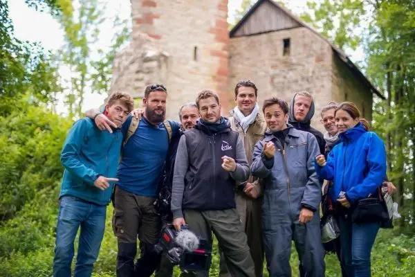 Gruppe von Personen posiert vor einer alten Mauer im Wald
