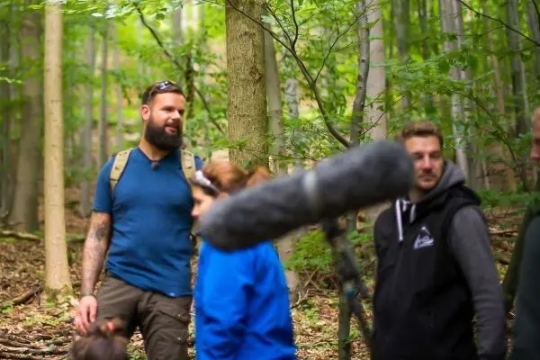 Gruppendynamik im Wald mit Mikrofon und Teilnehmern in Outdoor-Bekleidung