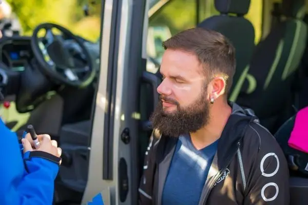 Mann sitzt im Fahrzeug und erhält eine Gesichtsbehandlung
