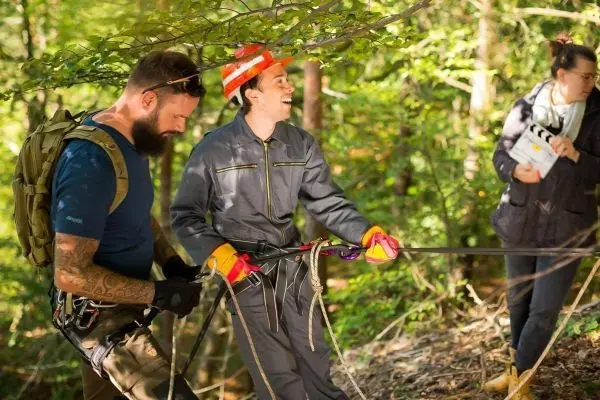 Zwei Personen halten ein Seil, während eine dritte Person eine Klappe hält