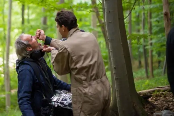 Zwei Personen in einem Wald, eine Person hält etwas vor das Gesicht der anderen