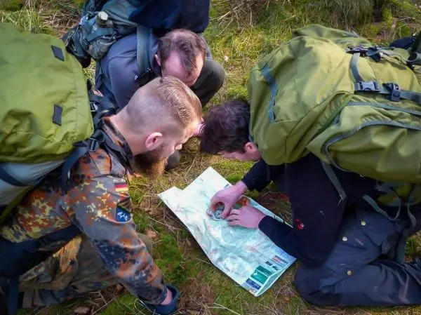 Gruppierung betrachtet gemeinsam eine Karte auf dem Boden im Wald