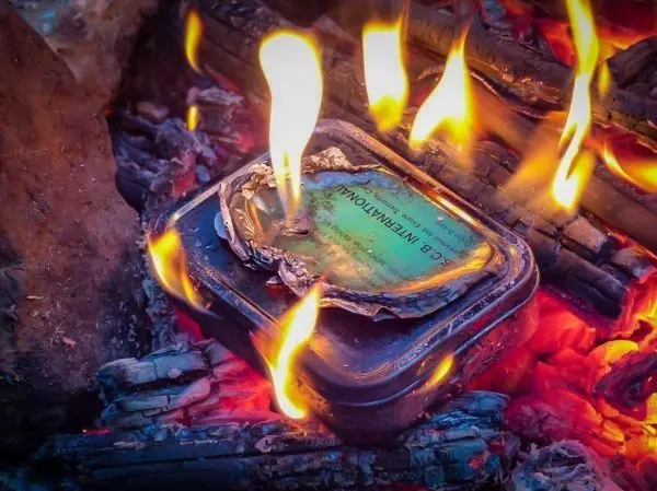 Kleine Flamme brennt auf einer Metallbox im Glutbett