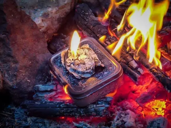 Kleine Flamme brennt in einer Dose auf glühenden Kohlen